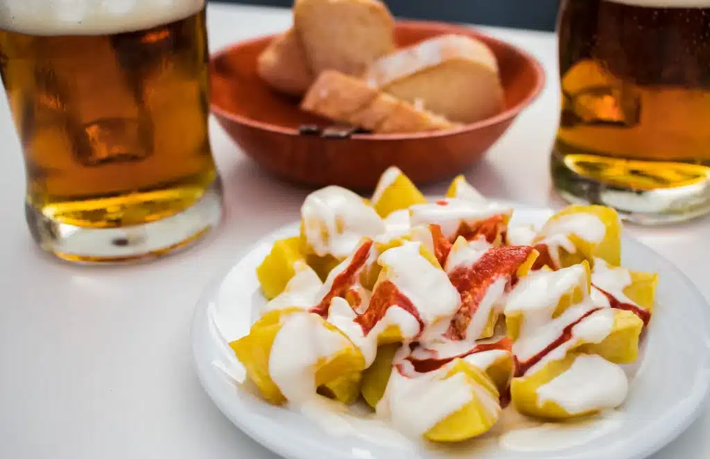 Comida tipica andaluza. Plato de patatas bravas acompañado de una caña de cerveza en una mesa de bar sevillano. Tapas Sevilla
