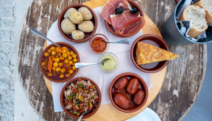 Selección de tapas andaluzas auténticas: chorizo, patatas, tortilla y garbanzos en restaurante cerca de Plaza de Armas, Sevilla.
